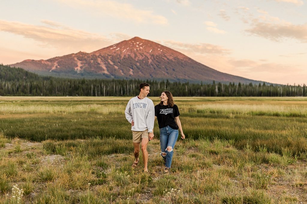 Sparks Lake Engagement - Couple in field with sunset mountain in background